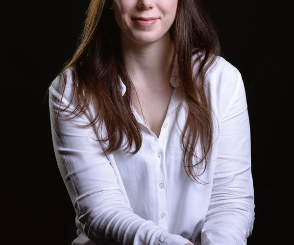 Portrait of a smiling confident woman, Daryna Ponomarenko, against a dark background.